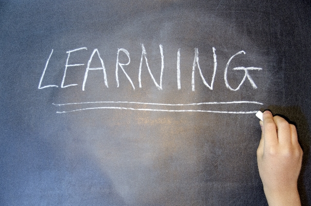 黒板にチョークでLEARNINGと書いている様子