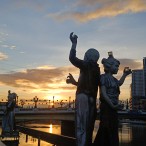 夕焼けの中で二人が背を合わせている様子